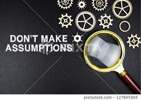 Don't Make Assumptions text message with magnifying glass on black background Don't Make Assumptions text message with magnifying glass on black background 127605808