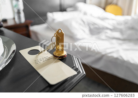 A hotel room key sits on the nightstand with a comfortable bed situated in the background 127606283