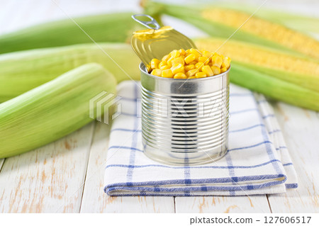Canned young corn grain on a light kitchen table, selective focus. Canned young corn grain on a light kitchen table, selective focus. 127606517