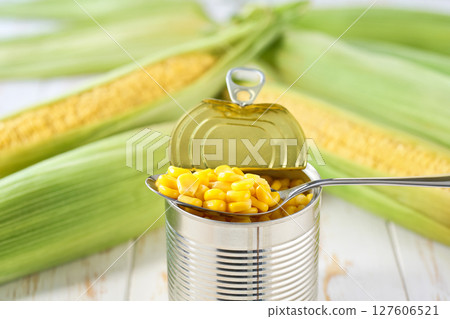 Canned sweet corn in metal can on a light kitchen table, selective focus. Canned sweet corn in metal can on a light kitchen table, selective focus. 127606521