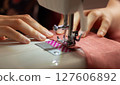 A woman sews on a sewing machine 127606892