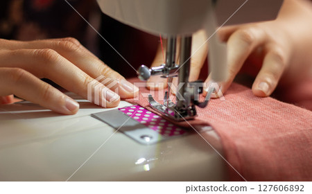 A woman sews on a sewing machine A woman sews on a sewing machine 127606892