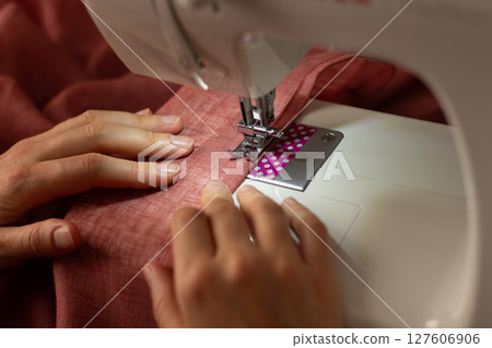 A woman sews on a sewing machine 127606906