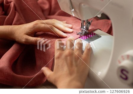 A woman sews on a sewing machine A woman sews on a sewing machine 127606926
