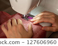 A woman sews on a sewing machine 127606960