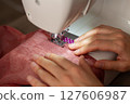 A woman sews on a sewing machine 127606987