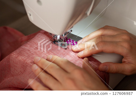 A woman sews on a sewing machine 127606987