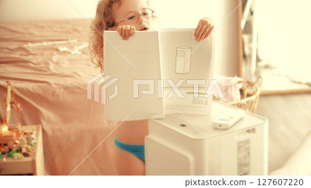 A girl with glasses stands by a portable air conditioner or AC, studying the user manual 127607220