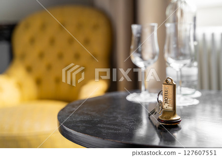An Elegant Hotel Room featuring a Key and Glassware elegantly arranged on a Table 127607551