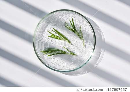 The texture of whey and rosemary in a petri dish on a background with streaks of shadows. 127607667