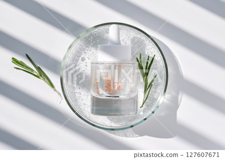 A bottle of rosemary serum in a petri dish. A bottle of rosemary serum in a petri dish. 127607671