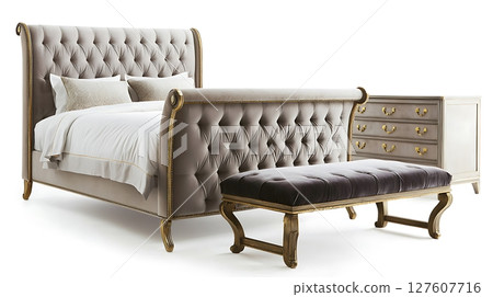 A bed with a white comforter and pillows, a black footstool 127607716