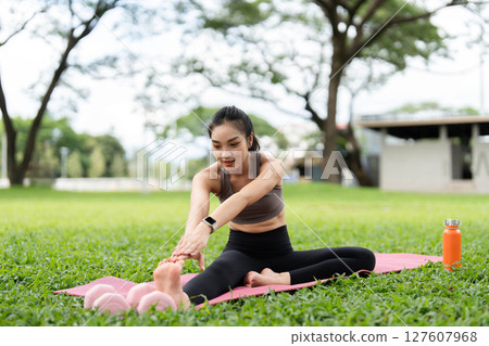 Yoga and fitness. Young woman reaching for her toes while practicing on a yoga mat. 127607968