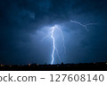 A lightning bolt is seen in the sky, illuminating the dark clouds 127608140