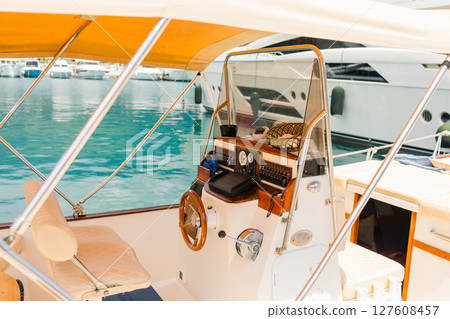 Cozy yacht cockpit with steering wheel and sea view. Nautical lifestyle, summer freedom and luxury leisure at marina harbor. Cozy yacht cockpit with steering wheel and sea view. Nautical lifestyle, summer freedom and luxury leisure at marina harbor. 127608457