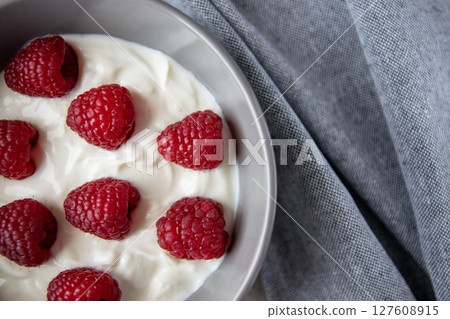 Natural fresh greek yogurt with raspberry berries in dark plate and napkin for healthy breakfast.  127608915