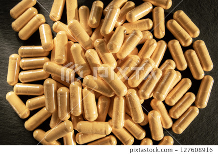 Much medical yellow pills and drugs in transparent package on the black stone background. Healthcare concept. BAA or biologically active additives. 127608916