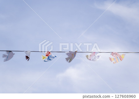 A Stunning Display of Colorful Paper Birds Elegantly Hanging Against a Bright Blue Sky 127608960