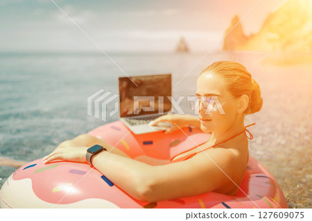 Woman laptop sea. Freelancer woman in sunglases floating on an inflatable big pink donut with a laptop in the sea. People summer vacation rest lifestyle concept Woman laptop sea. Freelancer woman in sunglases floating on an inflatable big pink donut with a laptop in the sea. People summer vacation rest lifestyle concept 127609075