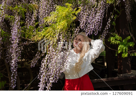 Wisteria Woman Portrait, Blonde poses by blooming Wisteria vine in daylight to enjoy spring. Wisteria Woman Portrait, Blonde poses by blooming Wisteria vine in daylight to enjoy spring. 127609091