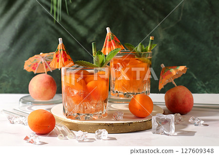 Alcoholic cocktail or punch, peach, apricot and mint berries on elegant background, minimalist concept for bar and holiday party, cafe, advertising banner, Modern still life with fruits. Alcoholic cocktail or punch, peach, apricot and mint berries on elegant background, minimalist concept for bar and holiday party, cafe, advertising banner, Modern still life with fruits. 127609348