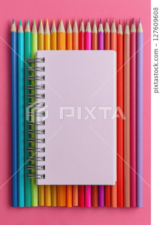 Colorful Flat Lay of Rainbow Pencils and Notebook on Pink Background 127609608
