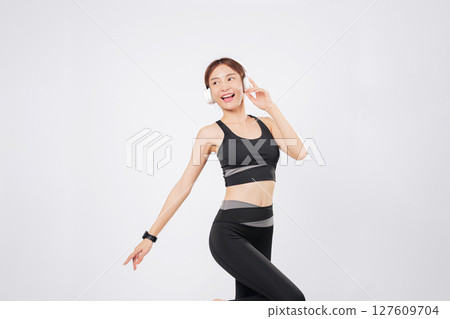 Dance takes over as this energetic woman listens to her favorite tune. Her smile widens as she begins to dance again, enjoying the healthy lifestyle she loves. isolated studio white background 127609704