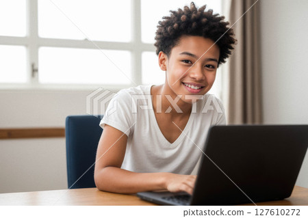 Cheerful Boy Engaged with Laptop in Bright Workspace Cheerful Boy Engaged with Laptop in Bright Workspace 127610272