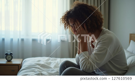 a sad woman sitting on her bed a sad woman sitting on her bed 127610569