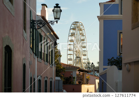 Colorful Alleyway Leading to a Giant Ferris Wheel 127611774