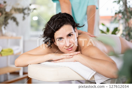Portrait of woman enjoying relaxing massage by professional masseur 127612034