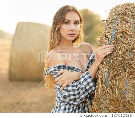 Young woman in shirt standing in hay field 127612126
