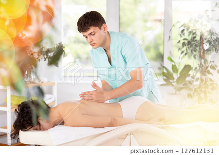 Young guy doing a back massage to adult woman Young guy doing a back massage to adult woman 127612131