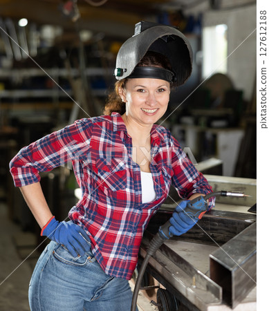 During manufacture of product, woman employee works with welding machine During manufacture of product, woman employee works with welding machine 127612188
