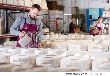 Young man pouring clay into mold 127612189