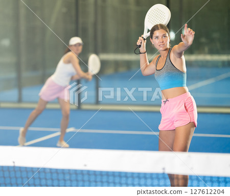 Young and adult women playing doubles tennis Young and adult women playing doubles tennis 127612204