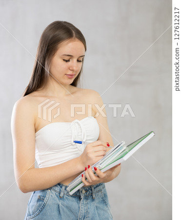 Young woman making notes in notebook in studio Young woman making notes in notebook in studio 127612217