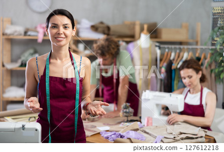 Female seamstress invites others to sew and work in sewing workshop 127612218