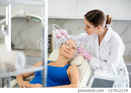 Professional beautician makes cryotherapy for rejuvenation woman face, anti aging procedure and shrink pores and repair damaged skin in salon Professional beautician makes cryotherapy for rejuvenation woman face, anti aging procedure and shrink pores and repair damaged skin in salon 127612239