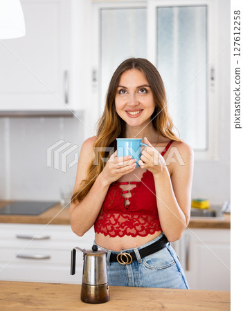 Smiling woman drinking coffee at home Smiling woman drinking coffee at home 127612258