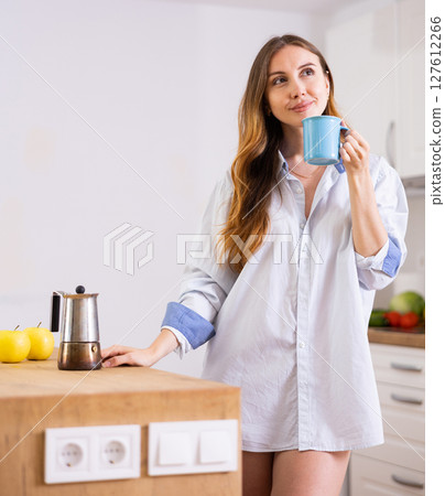 Woman drinking coffee at kitchen in morning Woman drinking coffee at kitchen in morning 127612266
