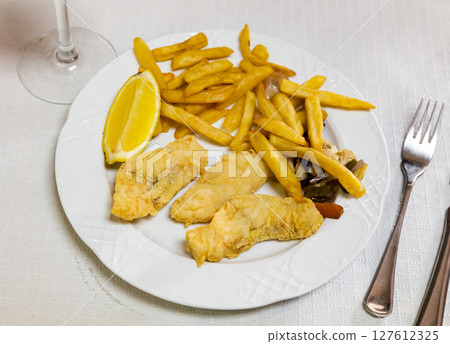 Battered fish with lemon and potatoes 127612325