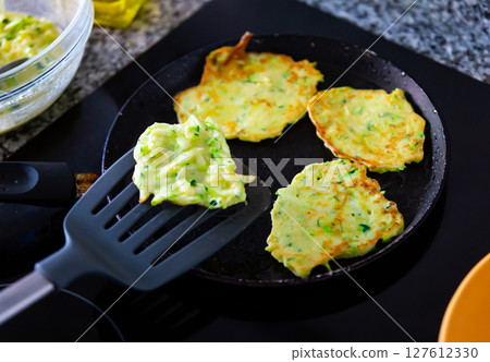 Zucchini pancakes cooked in frying pan Zucchini pancakes cooked in frying pan 127612330