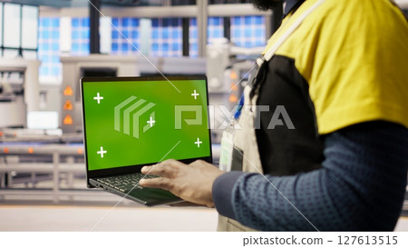 Factory engineer using green screen laptop to calibrate high tech machinery and analyze sensor data. Industrial plant employee uses chroma key notebook to troubleshoot assembly equipment, camera A Factory engineer using green screen laptop to calibrate high tech machinery and analyze sensor data. Industrial plant employee uses chroma key notebook to troubleshoot assembly equipment, camera A 127613515