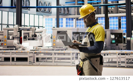 Smart factory specialist, testing automated systems, monitoring production performance. Industry 4.0 plant technician inspecting machinery to identify and optimize bottlenecks, camera A Smart factory specialist, testing automated systems, monitoring production performance. Industry 4.0 plant technician inspecting machinery to identify and optimize bottlenecks, camera A 127613517
