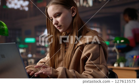 Female student makes final preparations for her university periodicals, combining research on books from the academy database and handwritten notes. Educated girl studying. Camera A. Female student makes final preparations for her university periodicals, combining research on books from the academy database and handwritten notes. Educated girl studying. Camera A. 127613575