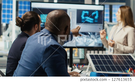 Executives and investors in photovoltaics plant reviewing solar technology reports, discussing future investment opportunities in renewable energy manufacturing, camera B 127613655