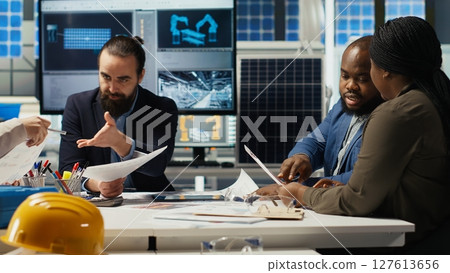 Engineers study detailed schematics of solar panel assembly lines, refining production layouts and component configurations for efficiency, outlining documentation for new prototypes, camera B 127613656