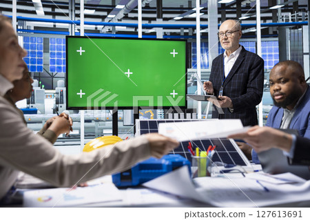 Industrial plant managers showcase product innovations using chroma key display. Factory businessmen doing sales presentation for customers, showing solar panel solutions using isolated screen monitor Industrial plant managers showcase product innovations using chroma key display. Factory businessmen doing sales presentation for customers, showing solar panel solutions using isolated screen monitor 127613691