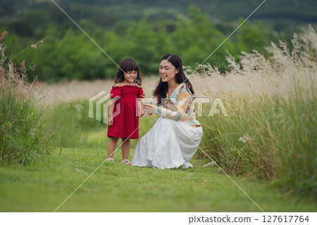 happy mother and daughter playing grass flower in field 127617764